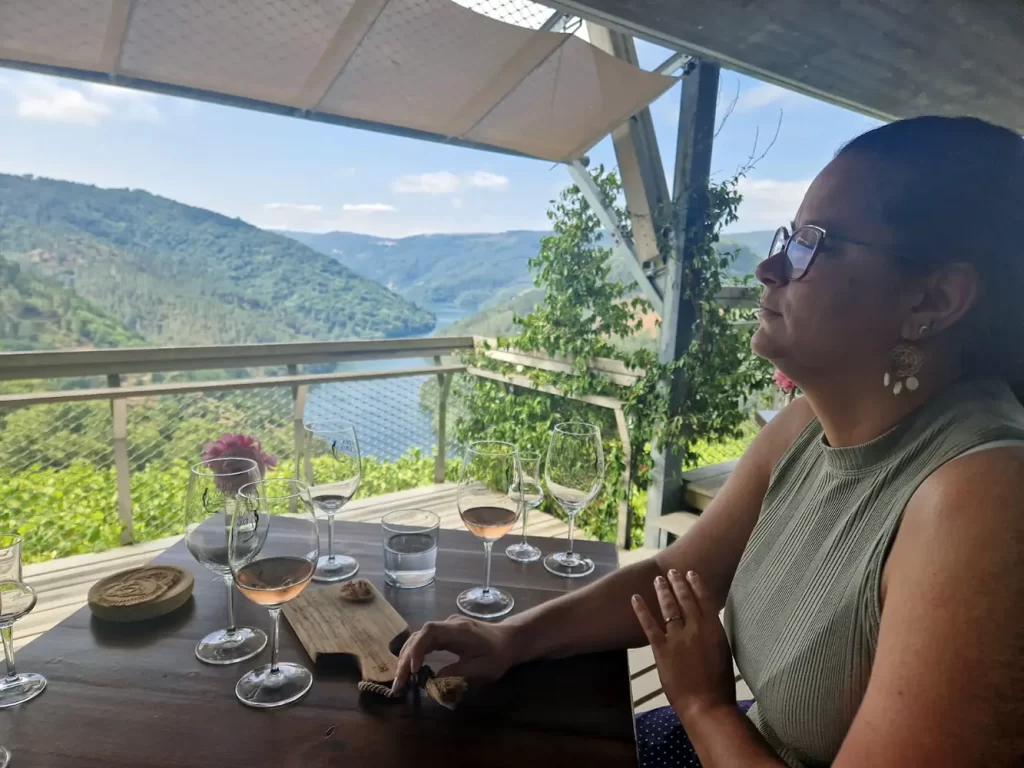 Mulher apreciando vinhos na área de degustação da Adegas Moure, com vista para o rio.