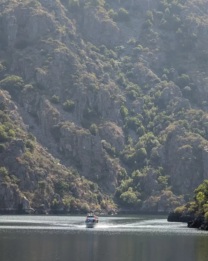 Catamarã navegando pelo Rio Sil, rodeado por imponentes desfiladeiros rochosos.