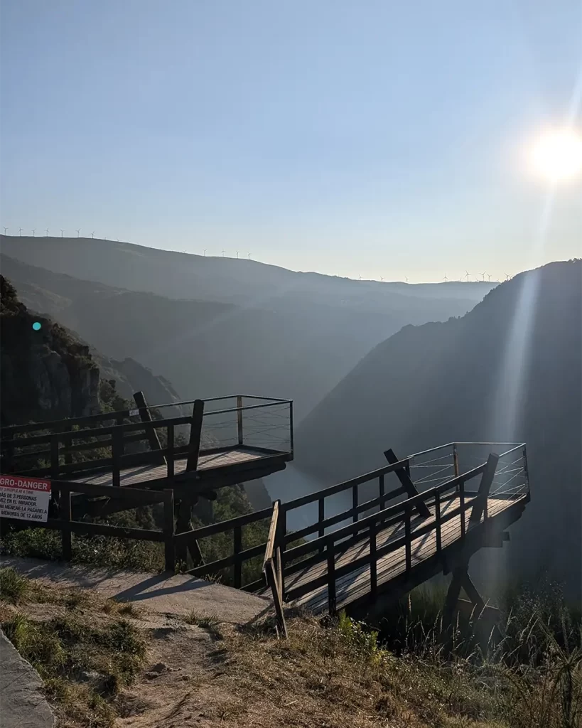 Duas plataformas de madeira do Mirador, projetadas sobre o vale com vista para as montanhas e o Rio Sil, iluminadas pela luz do sol.