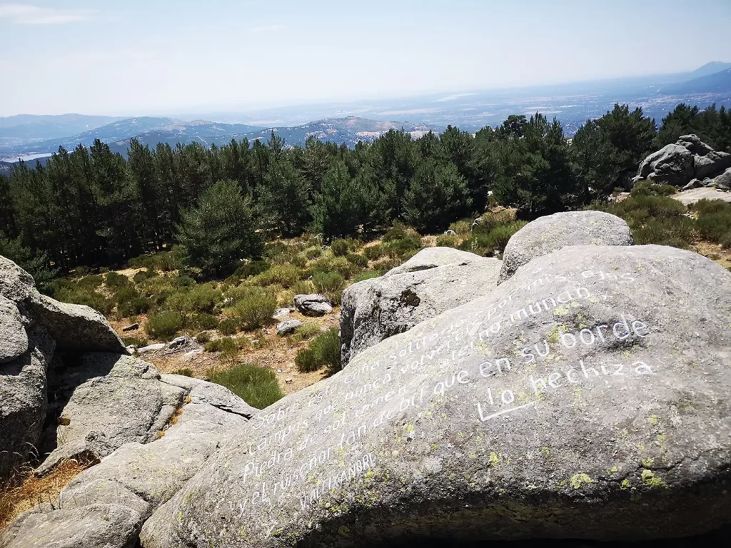 Rochas com inscrições poéticas no Mirador de los Poetas, com vista para a floresta e montanhas ao fundo.