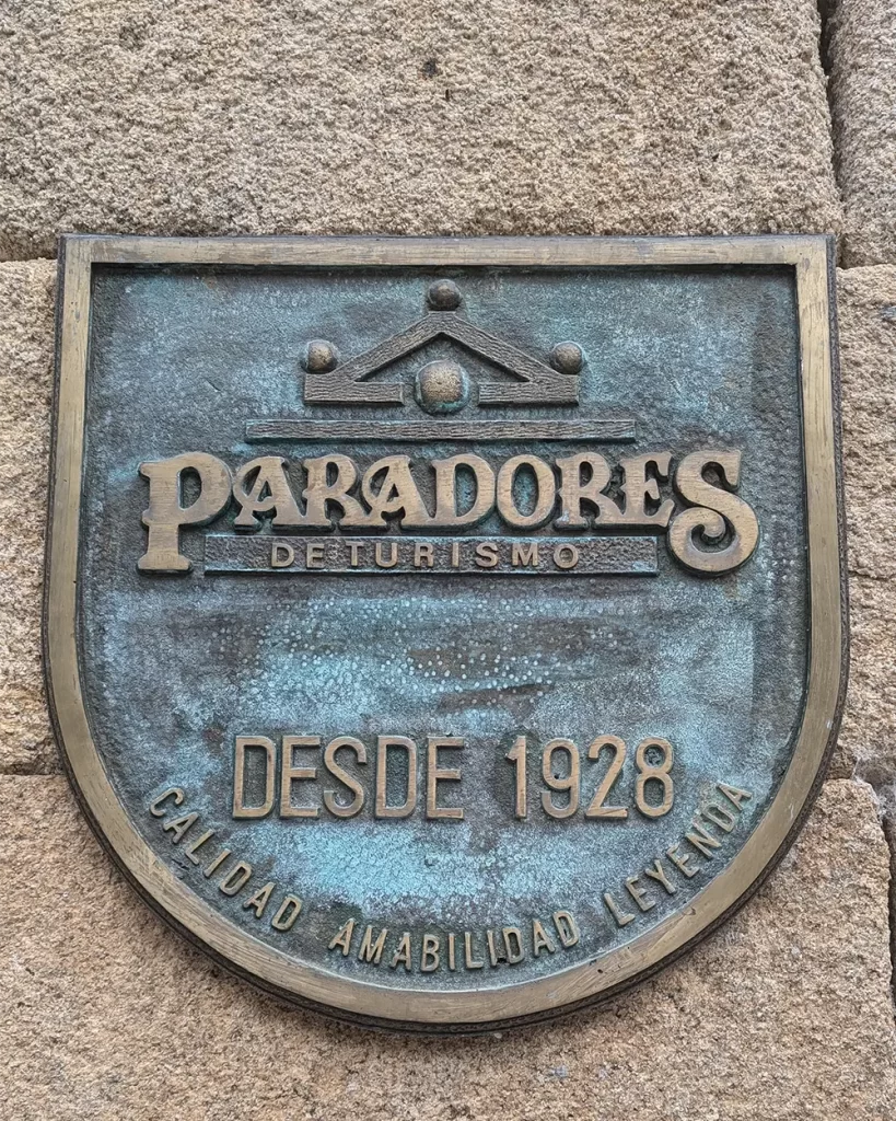 Placa de bronze dos Paradores de Turismo da Espanha, com o texto "Desde 1928, Calidad, Amabilidad, Leyenda."