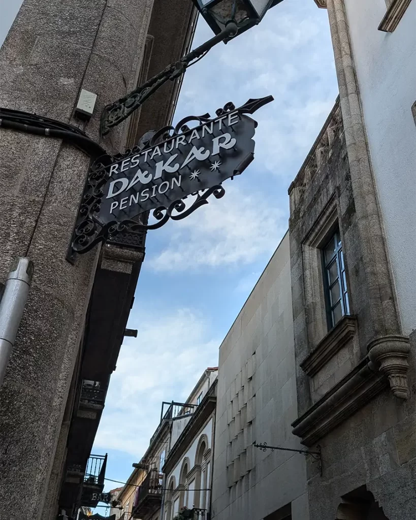 Placa do Restaurante Dakar, um dos bares que marcam o final da rota 'Paris-Dakar', localizada em uma rua estreita de Santiago de Compostela.