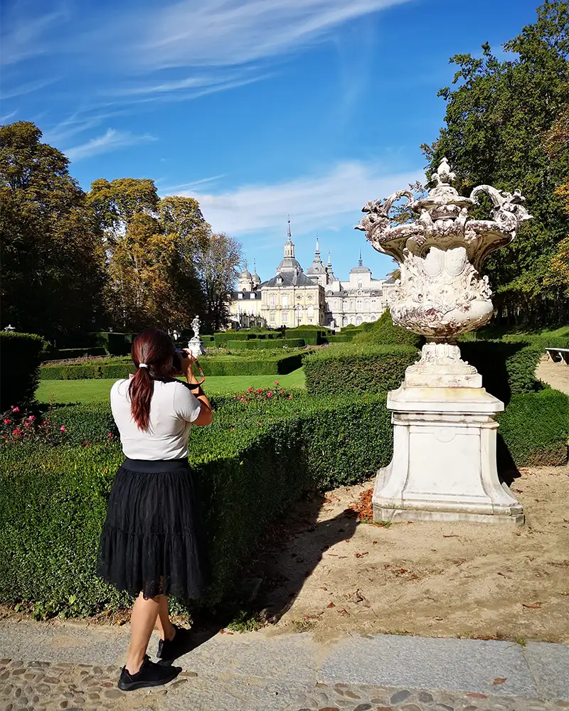 Eu tirando uma foto dos jardins do Palácio Real de La Granja, com esculturas e o palácio ao fundo.