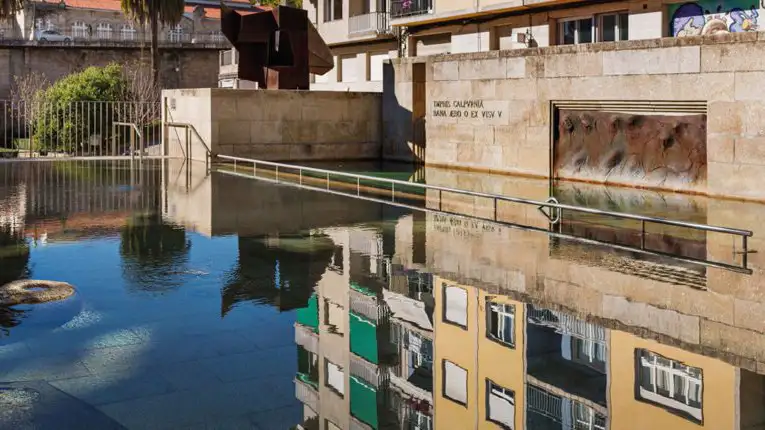 Piscina termal pública das Burgas, localizada no centro de Ourense, com reflexo dos prédios nas águas quentes.