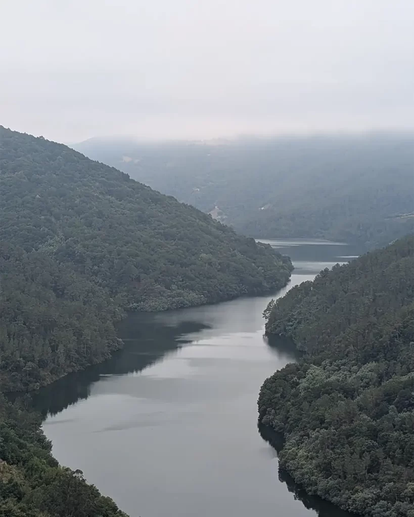 Vista aérea do rio Sil cercado por colinas verdejantes em um dia nublado.