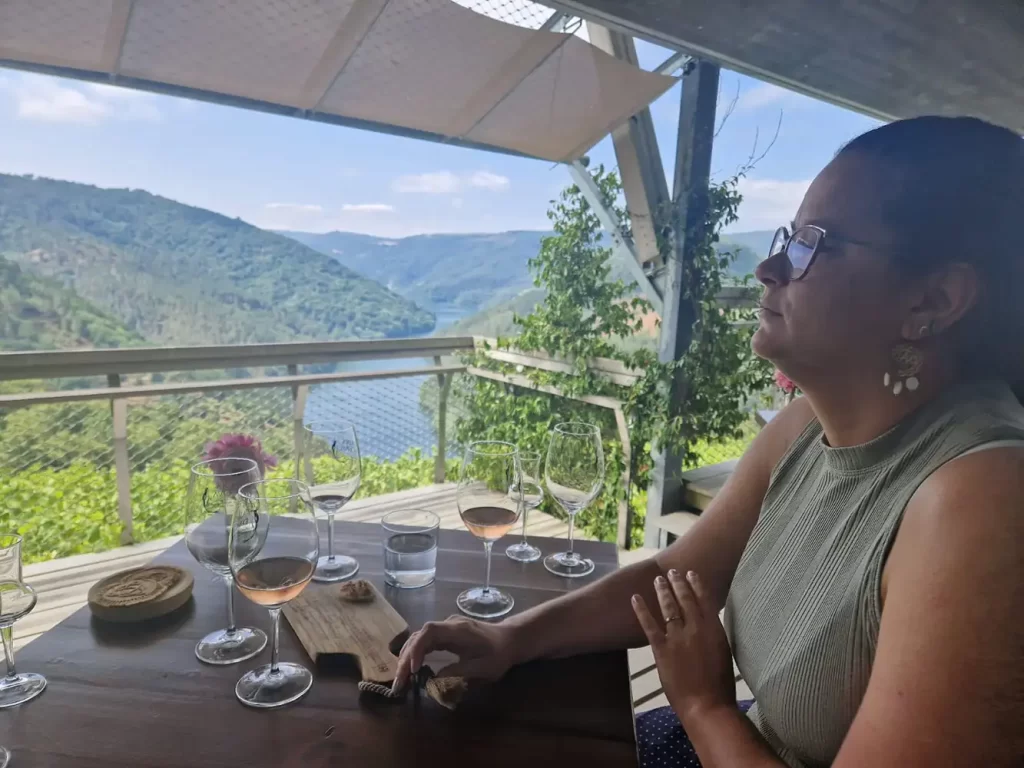 Degustação de vinhos com vista para o rio Sil, com taças de vinho rosé e branco dispostas sobre a mesa.