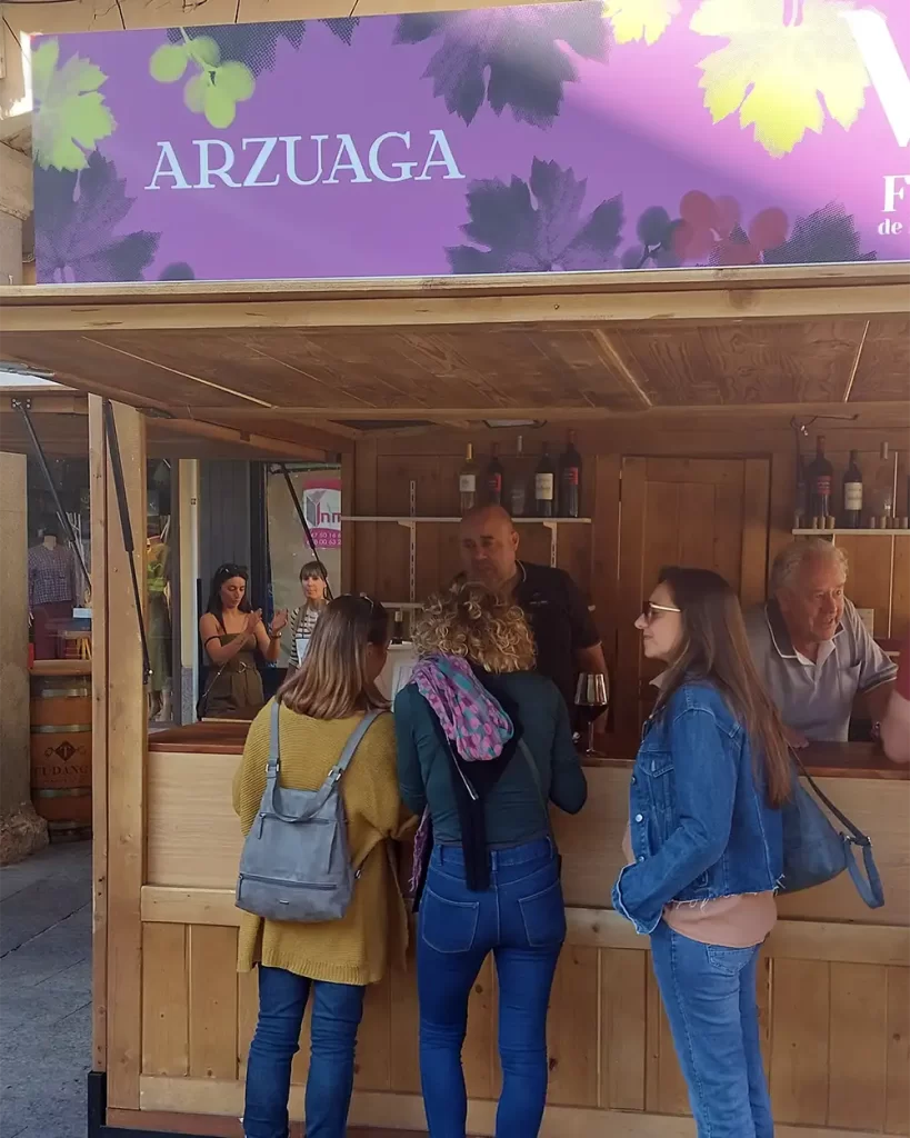 Pessoas degustando vinhos no stand da vinícola Arzuaga durante a Festa da Vindima em Ribera del Duero.