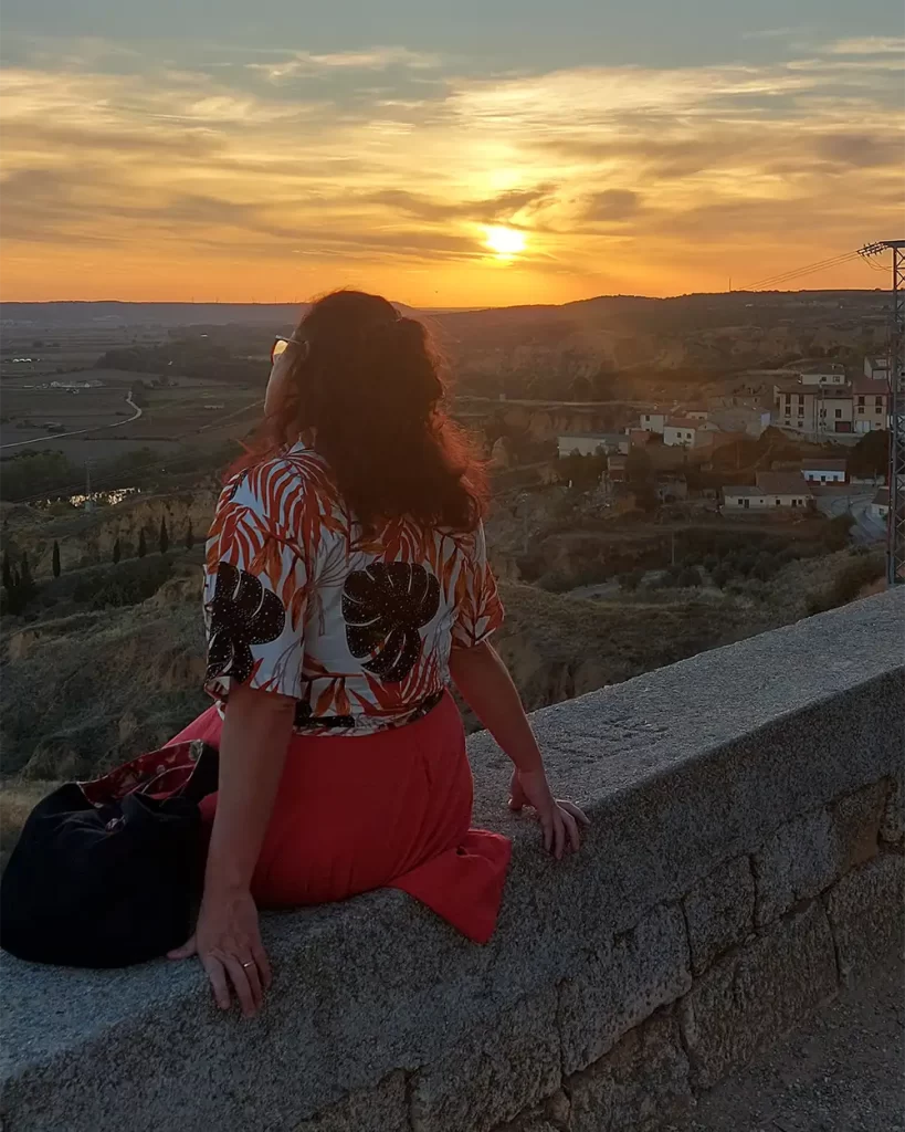 Pessoa sentada apreciando o pôr do sol com vista para a cidade de Toro e vinhedos.