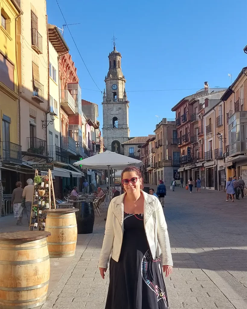 Pessoa posando em uma rua de Toro com uma igreja histórica ao fundo.