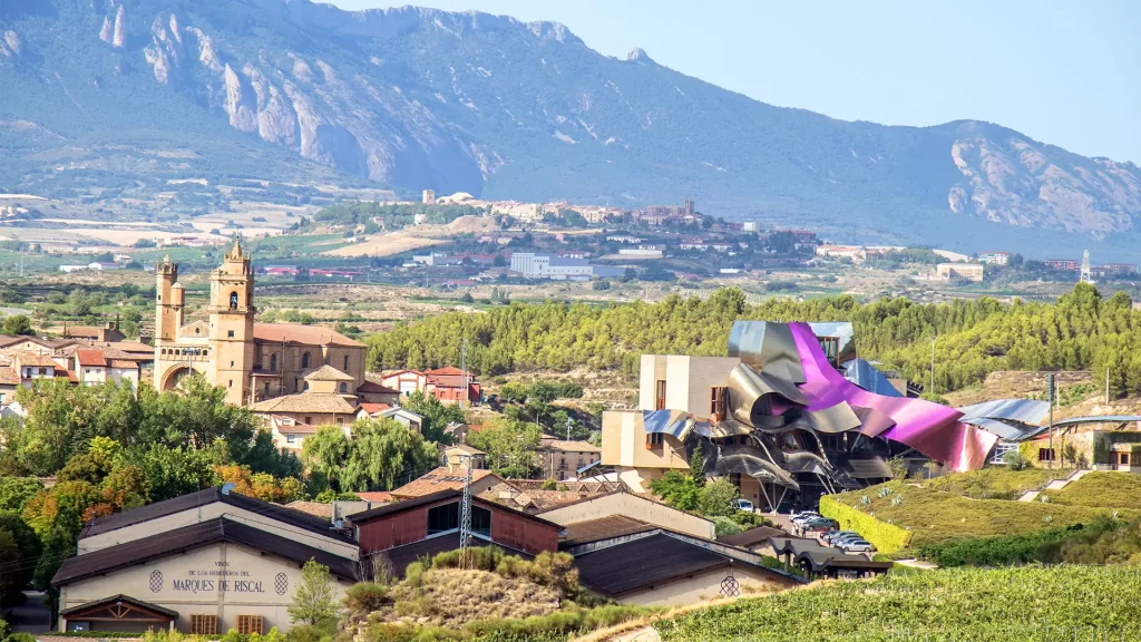 Paisagem de Elciego, em Rioja, com vinhedos, uma igreja histórica e o edifício moderno da vinícola Marqués de Riscal.