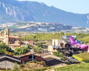 Paisagem de Elciego, em Rioja, com vinhedos, uma igreja histórica e o edifício moderno da vinícola Marqués de Riscal.