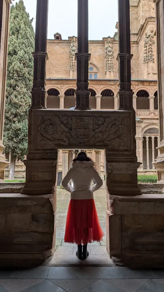 Pessoa observando o claustro do Convento de San Esteban através de uma passagem decorada.