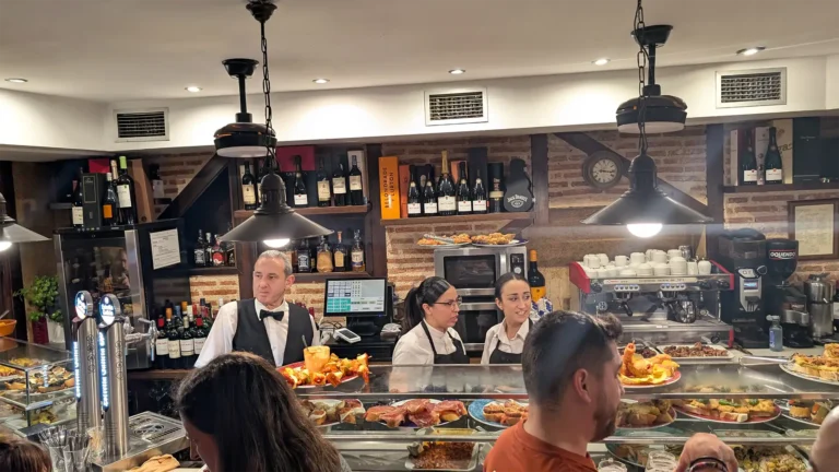 Balcão com variedade de tapas e equipe de atendimento no bar Hostería Casa Vallejo em Salamanca