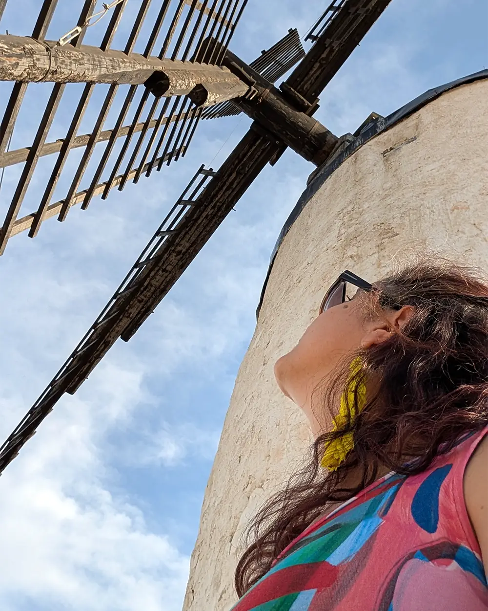 Detalhe das pás de um moinho de Consuegra com visitante observando de perto a estrutura