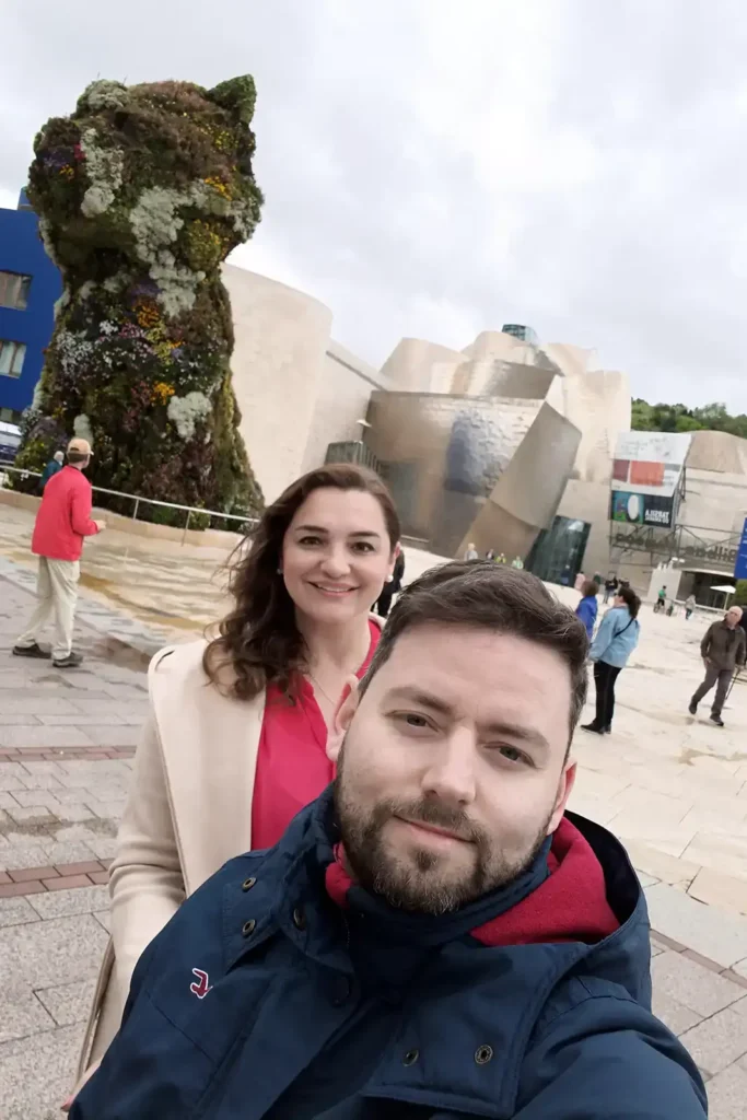 Foto em frente ao Museu Guggenheim Bilbao com a escultura floral Puppy ao fundo