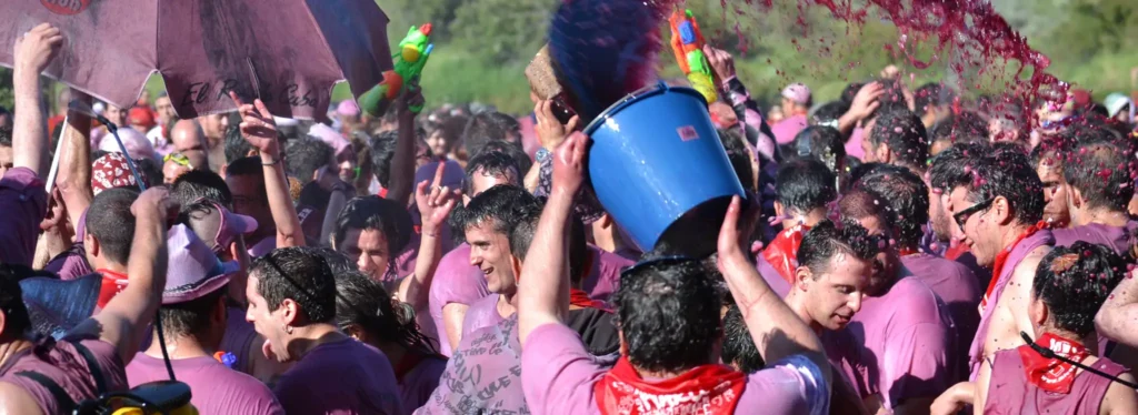 Momento exato em que um homem joga um balde de vinho tinto sobre a multidão durante o auge da Batalha de Vinho de Haro.