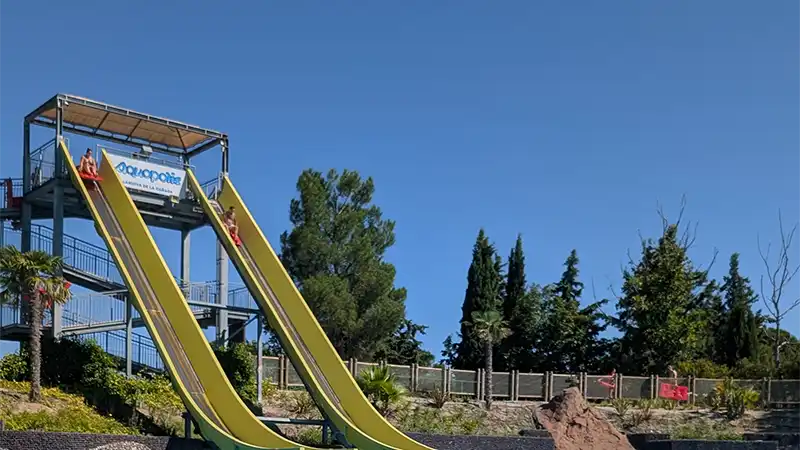 Pessoas descendo nos toboáguas amarelos da atração Splash no parque aquático Aquópolis, em um dia de céu azul.