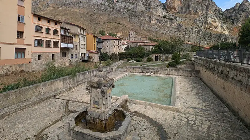 Lavadouro público de pedra de Pancorbo, com o vilarejo e as grandes rochas do desfiladeiro ao fundo.
