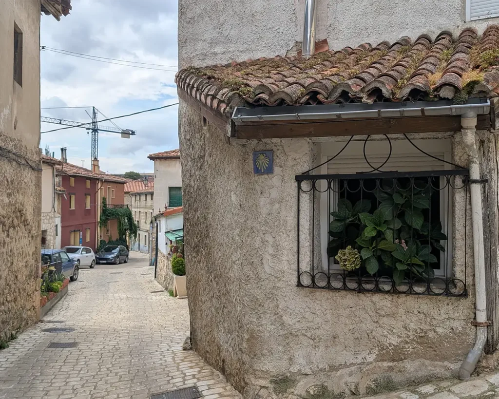 Vieira do Caminho de Santiago em um azulejo na parede de uma casa rústica em uma rua de paralelepípedos de Pancorbo.