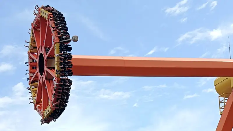 O pêndulo gigante da atração radical Synkope no Terra Mítica, girando com visitantes a grande altura contra o céu azul.