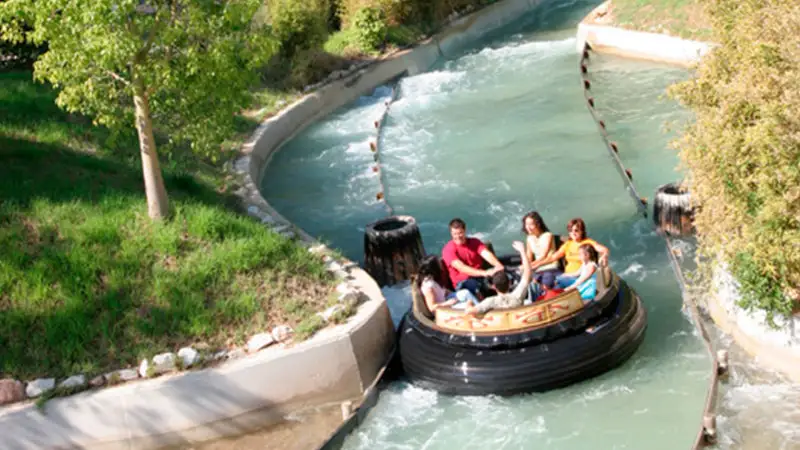 Visitantes em um bote circular navegam pelas águas revoltas da atração aquática Rápidos de Argos no parque Terra Mítica.