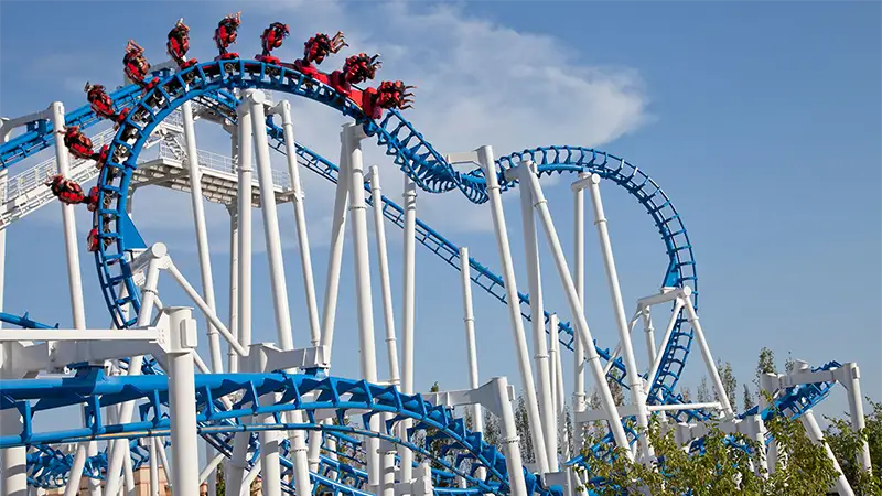 A montanha-russa invertida Titánide no Terra Mítica, com seu trem passando por um dos loopings em sua estrutura azul e branca.
