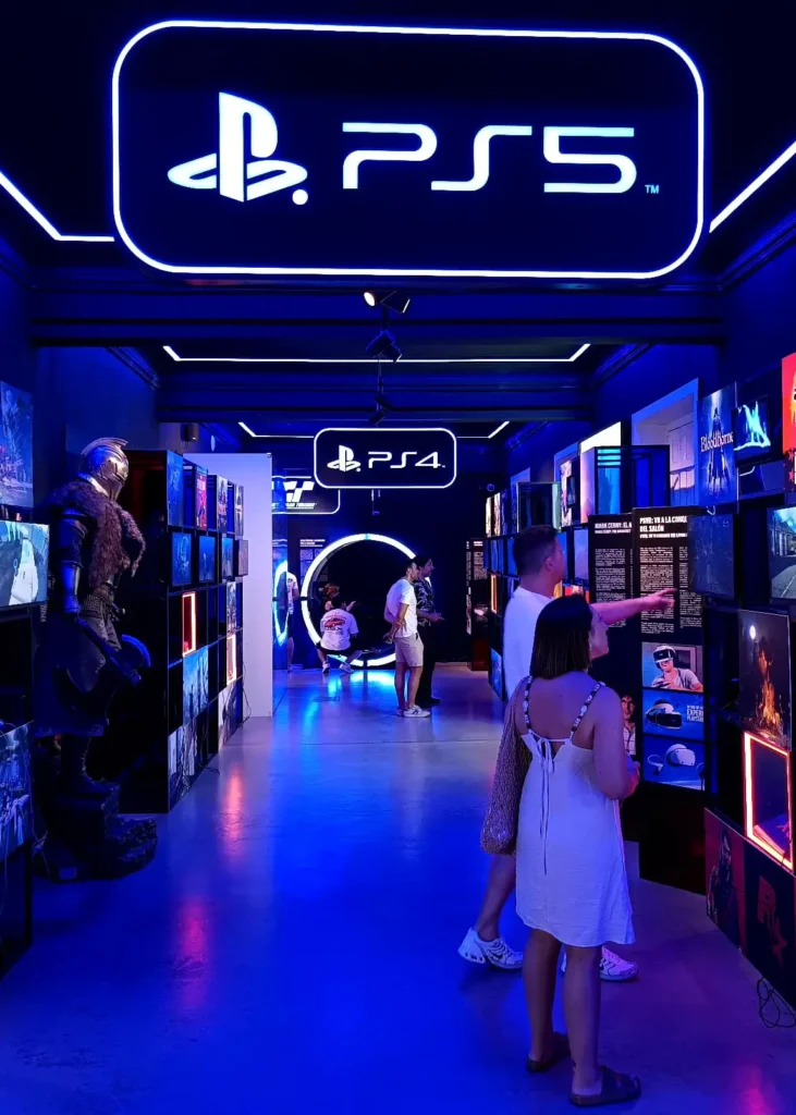 Sala do OXO Madrid dedicada ao PlayStation 4 e PlayStation 5, com painéis iluminados e vitrines de jogos.