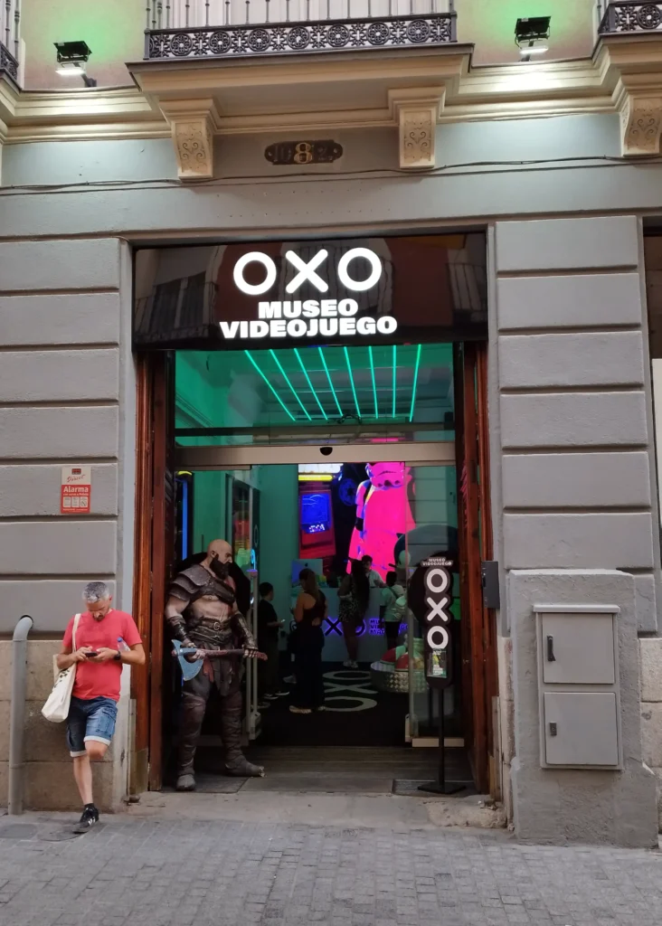 Fachada do OXO Museo del Videojuego em Madrid, com iluminação colorida e estátua na entrada.