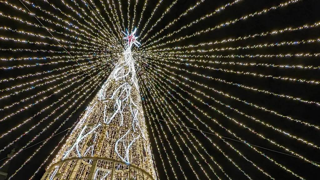 Árvore de Natal iluminada na Espanha com milhares de luzes formando um teto luminoso durante a noite.