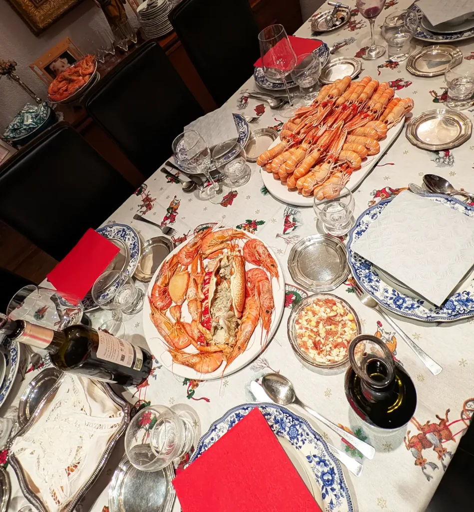 Mesa posta para a ceia de Natal na Espanha, com frutos do mar variados, vinho e pratos tradicionais servidos sobre toalha temática.