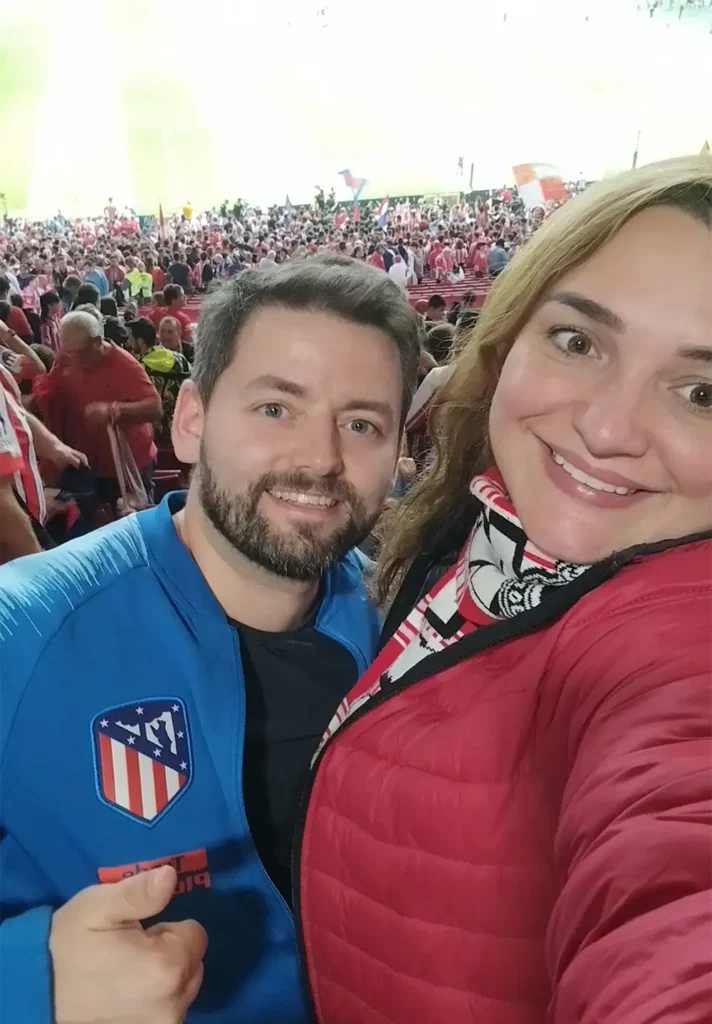 Nós nas arquibancadas do Estádio Metropolitano durante o jogo do Atlético de Madrid, com a torcida ao fundo.