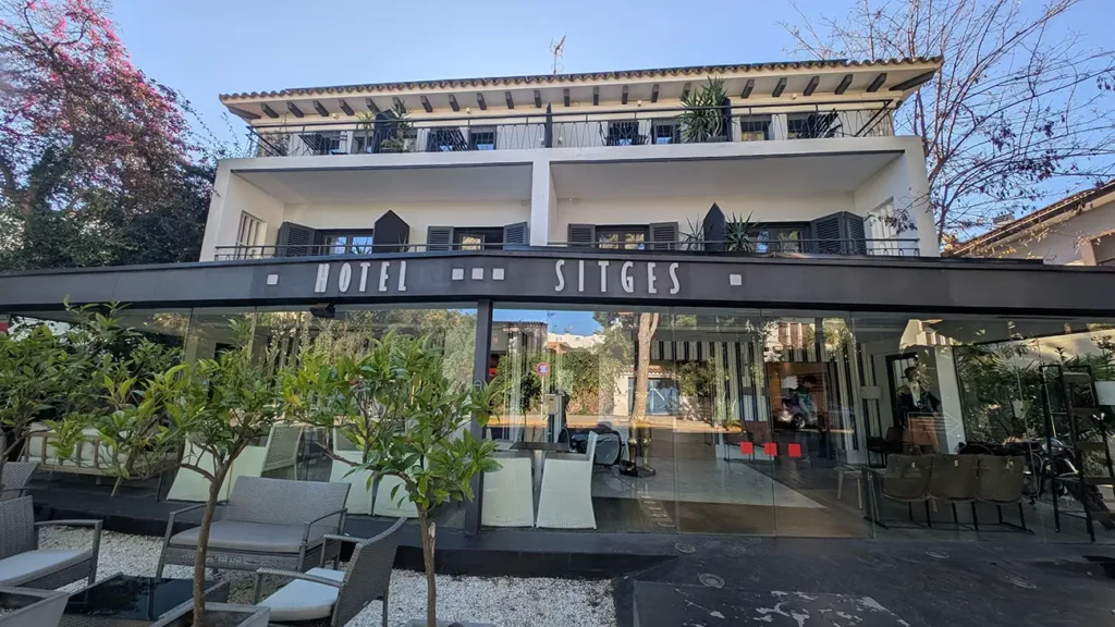 Fachada do Hotel Sitges, edifício moderno com jardim, terraço e entrada envidraçada, localizado na cidade de Sitges.