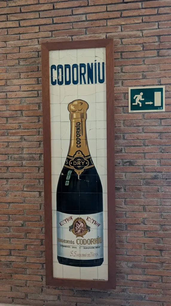 Painel decorativo com garrafa histórica da Codorníu em parede de tijolo