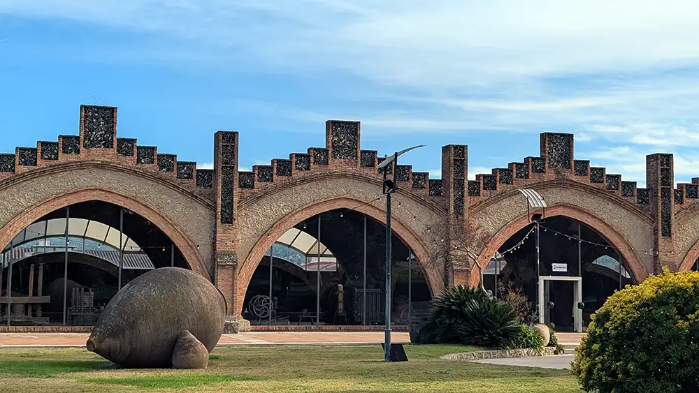 Fachada do edifício histórico da Codorníu com arcos de tijolo e jardins