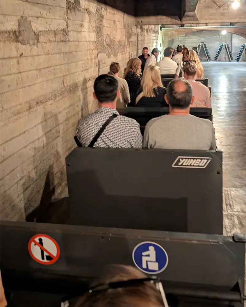 Visitantes sentados em vagão durante percurso pelos túneis subterrâneos da Codorníu