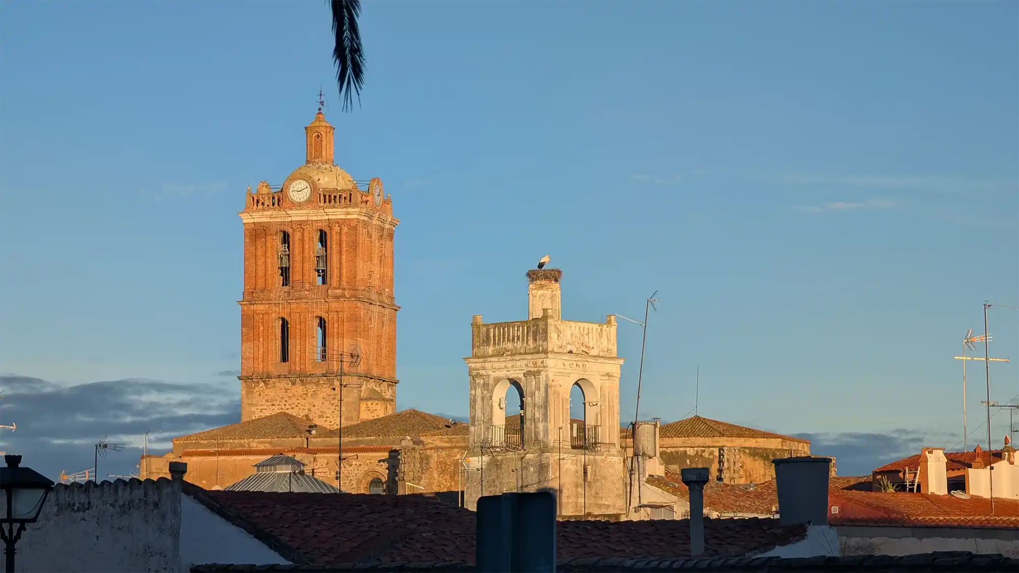 Vista del casco histórico de Zafra, en Extremadura, con la torre de la iglesia y edificios tradicionales iluminados por la luz del atardecer.