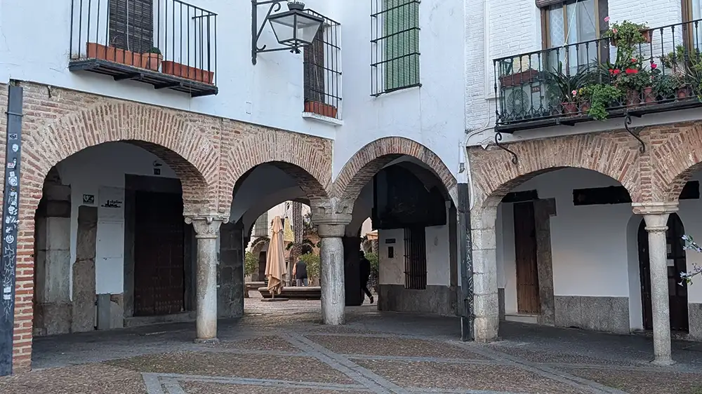 Arquillo del Pan ligando a Plaza Grande à Plaza Chica, com arcadas de pedra e vista para a praça central de Zafra.