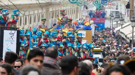 Desfile de carnaval em Cádiz com foliões fantasiados em carros alegóricos e multidão ocupando as ruas do centro histórico.