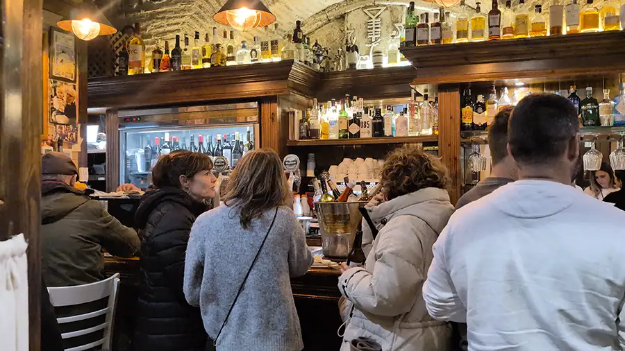 Interior da Taberna Embrujo em Toledo com clientes ao balcão e ambiente tradicional de tapas no centro histórico.