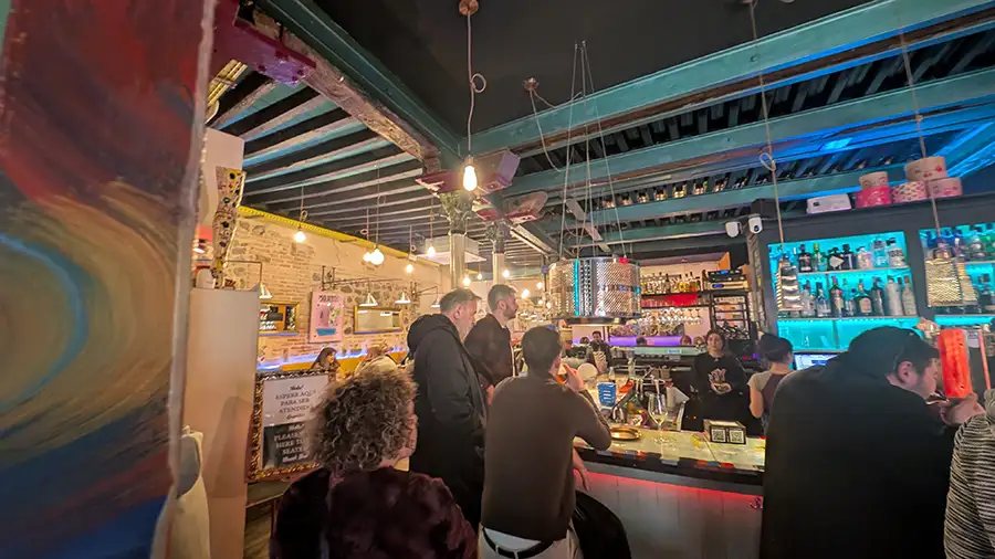 Interior do bar La Malquerida em Toledo com clientes ao balcão e ambiente de tapas no centro histórico.