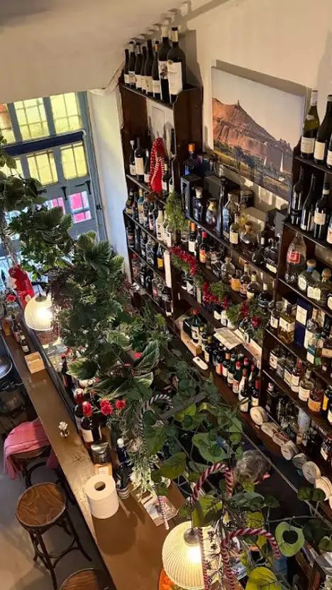 Interior da Taberna La Tintilla em Toledo com prateleiras de vinhos e ambiente acolhedor no centro histórico.