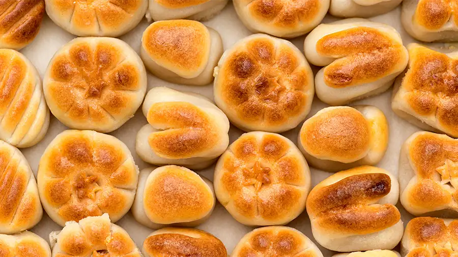 Marzipã tradicional de Toledo servido em prato com doces de amêndoa assados e ingredientes como amêndoas e açúcar ao fundo.