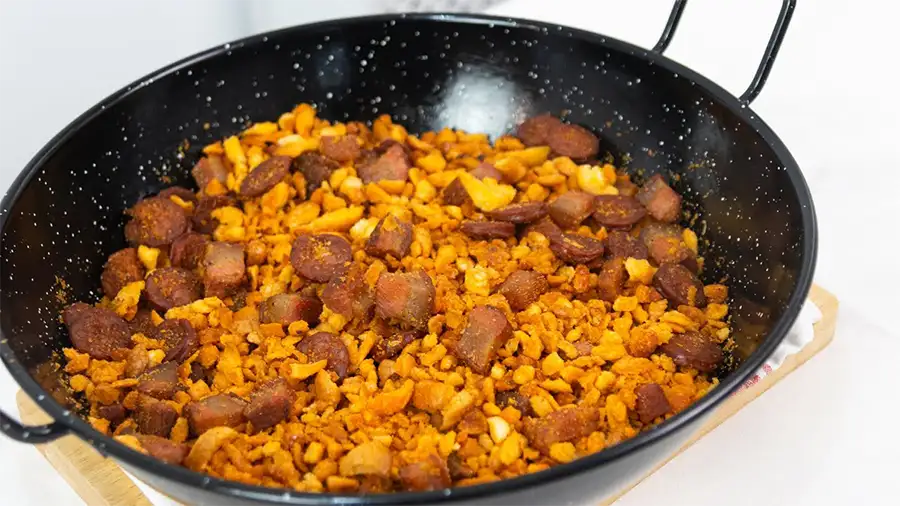 Migas manchegas servidas em prato de barro com linguiça, torresmo, alho, ovos fritos e pimentões, prato típico de Castilla-La Mancha.