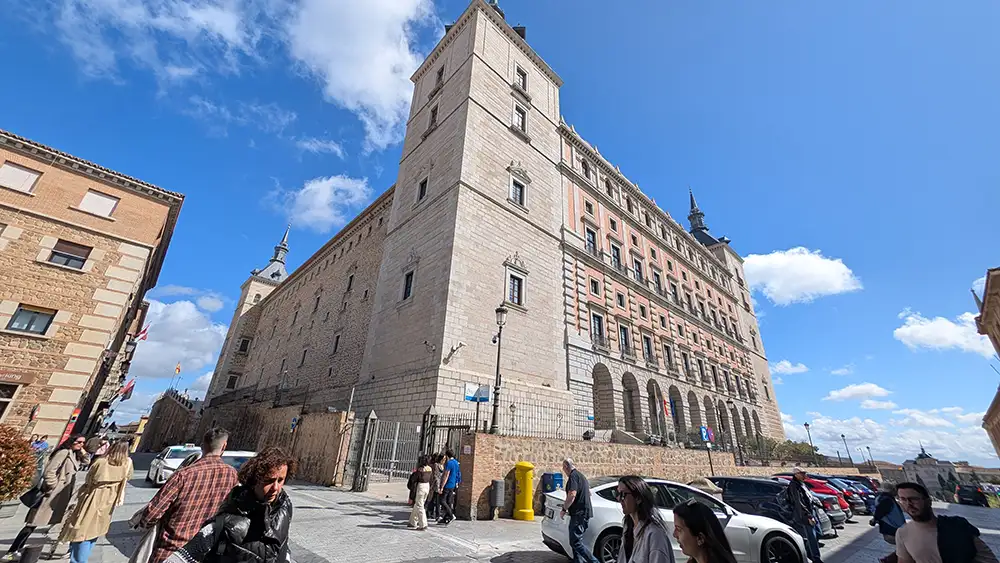 Alcázar de Toledo visto da rua com fachada monumental e visitantes ao redor.
