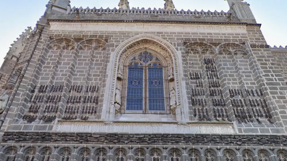 Janela e fachada gótica do Mosteiro de San Juan de los Reyes em Toledo com correntes históricas.