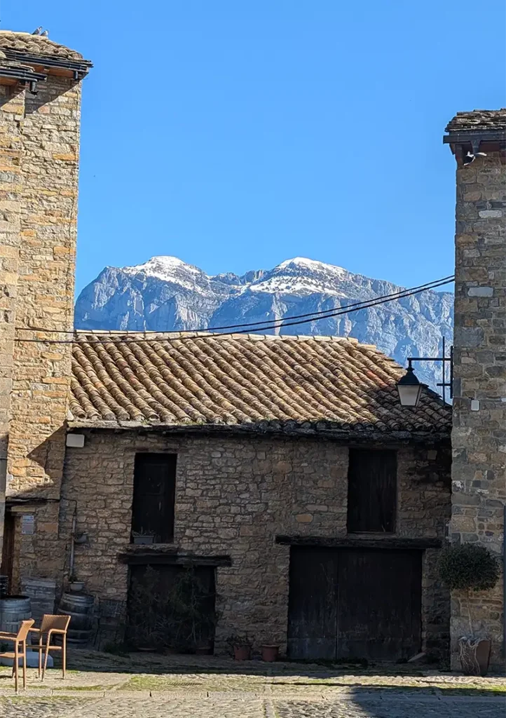 Casas de pedra do centro histórico de Aínsa com os Pirineus nevados ao fundo, Huesca, Aragão.
