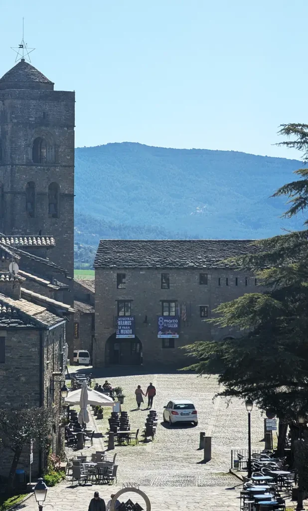 Praça maior de Aínsa com a torre da igreja, mesas de restaurante e as montanhas ao fundo, Huesca, Aragão.