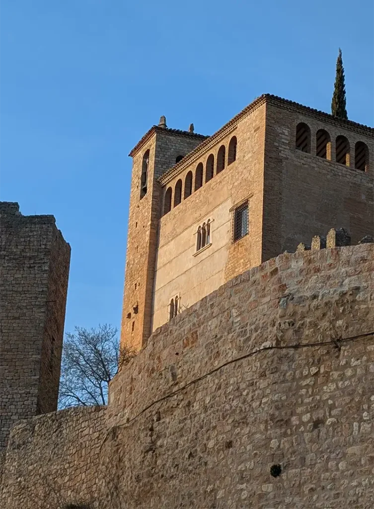 Torre e muralhas da Colegiata de Alquézar vista de baixo, com céu azul ao fundo, Huesca, Aragão.