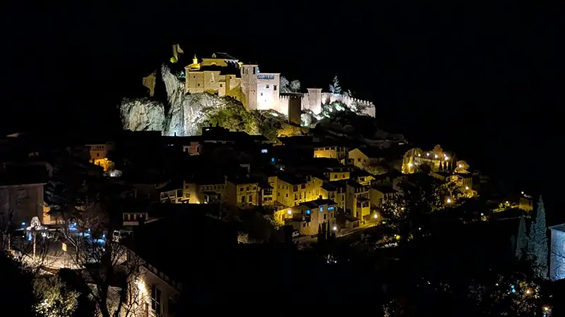 Vista noturna de Alquézar com a Colegiata iluminada no alto da rocha e as casas de pedra espalhadas pelo morro, província de Huesca, Aragão.