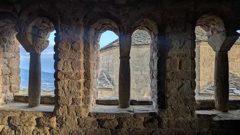 Série de arcos românicos de pedra no interior do Castillo de Loarre com vista para o exterior ao fundo, Huesca, Aragão.
